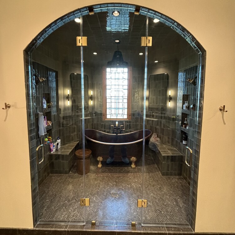 Arched glass steam shower room next to a freestanding soaking tub