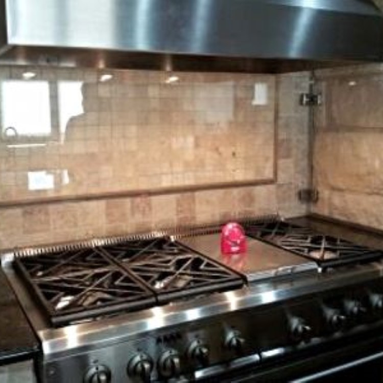 Custom glass backsplash panel behind a stainless kitchen range