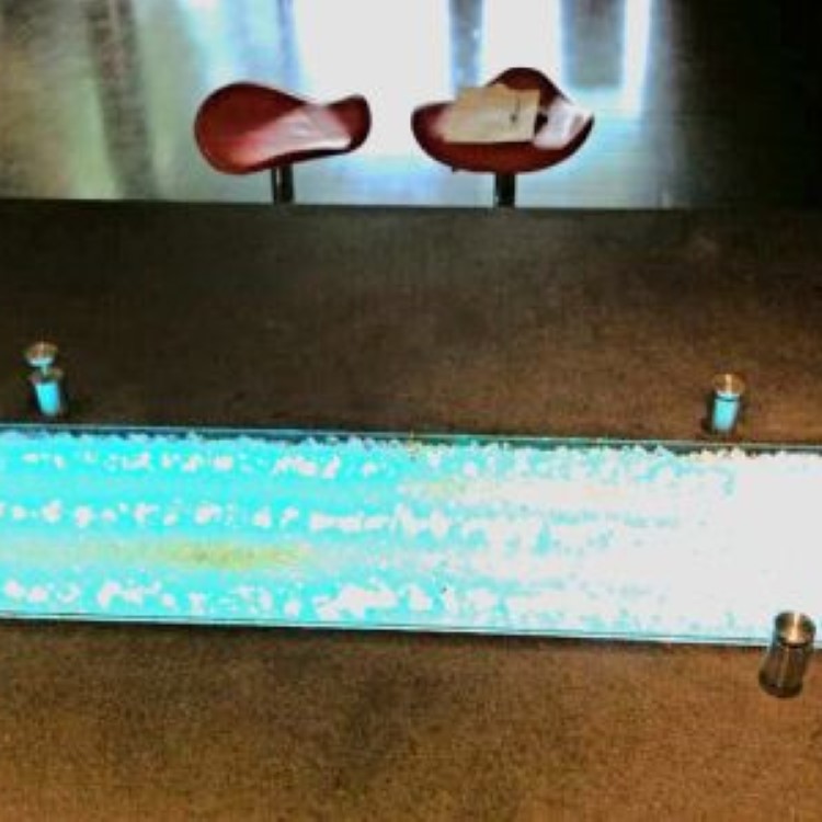 Custom glass table top with polished edges over a lit base