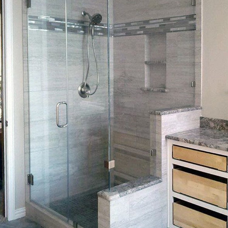 Frameless 90-degree glass shower enclosure with a tiled corner bench