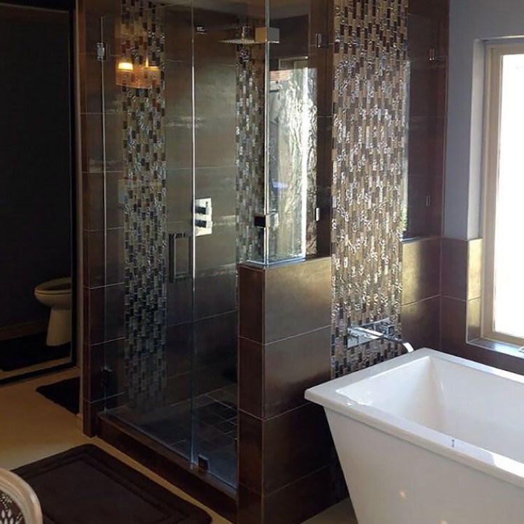 Frameless glass shower enclosure in front of a mosaic tile feature wall