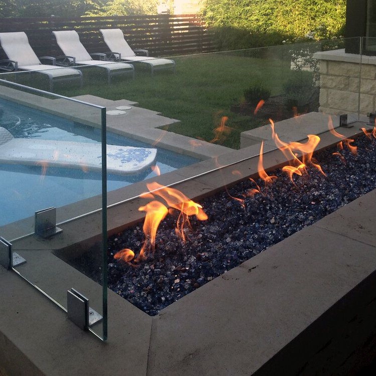Frameless glass screen around a fire pit on a pool deck