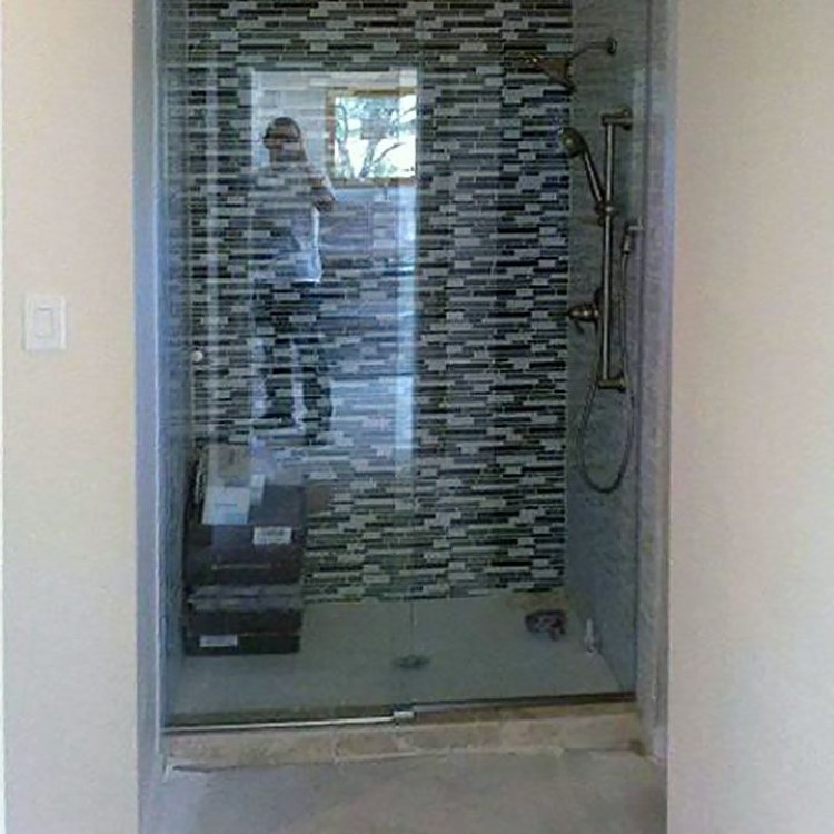 Sliding glass shower doors in front of a vertical mosaic tile accent