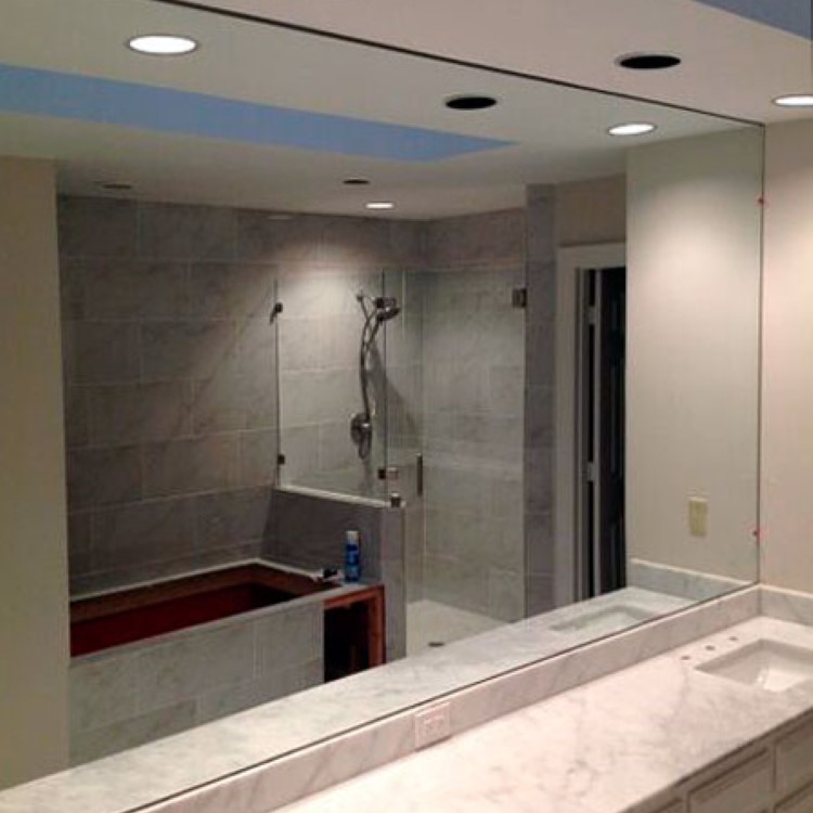 Wall-to-wall custom bathroom mirror above a stone vanity top