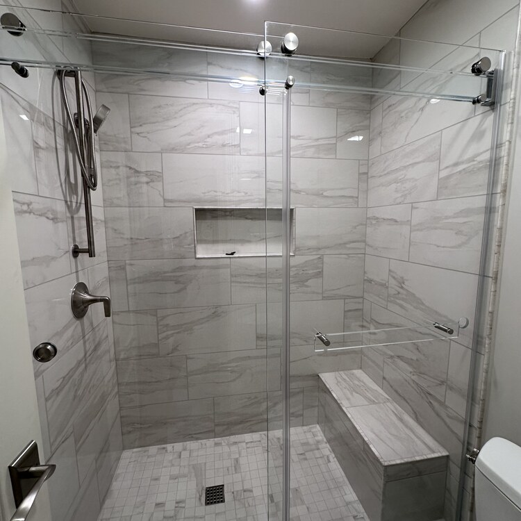 Frameless Shower Enclosure with Marble Slab Walls Frameless glass shower enclosure set against full marble slab walls