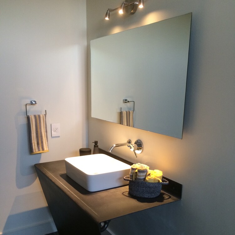 Frameless custom vanity mirror mounted above a floating wood vanity