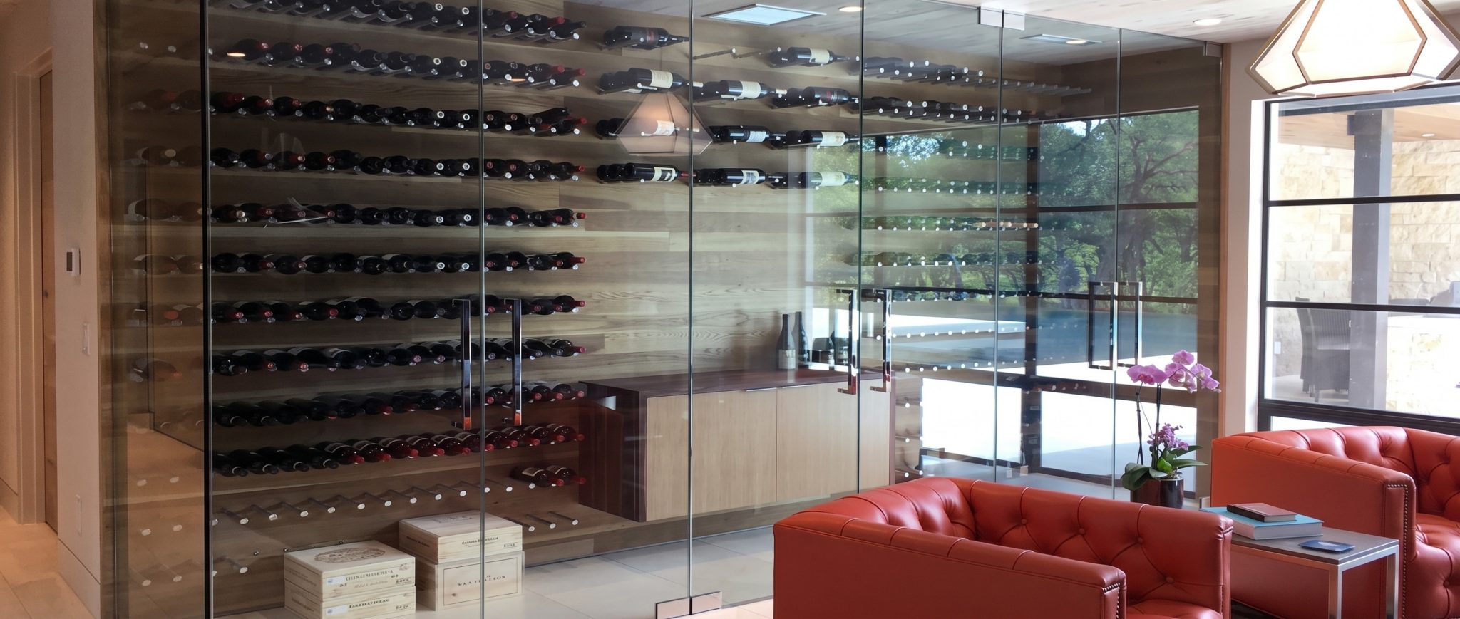 Large glass wine room with black racking and a leather club chair
