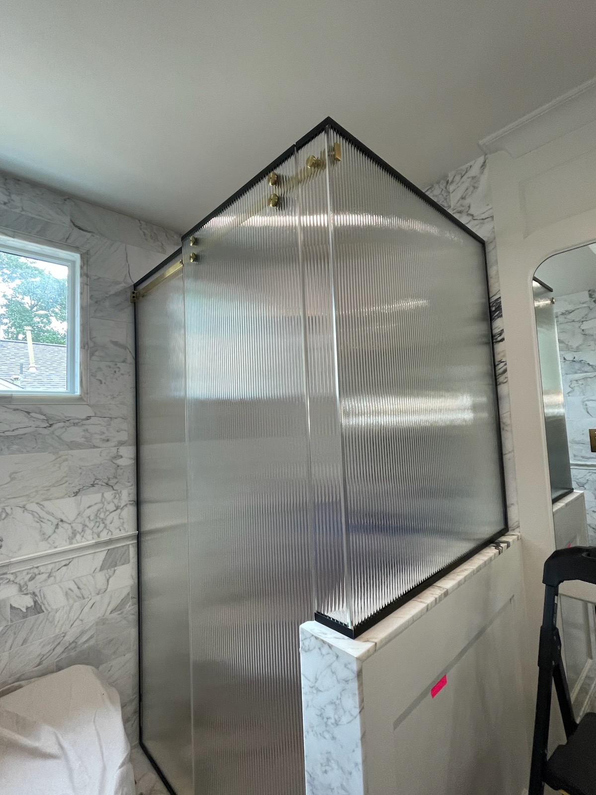 Custom 90-degree Serenity slider in 3/8-inch reeded glass over a pony wall in Austin, TX