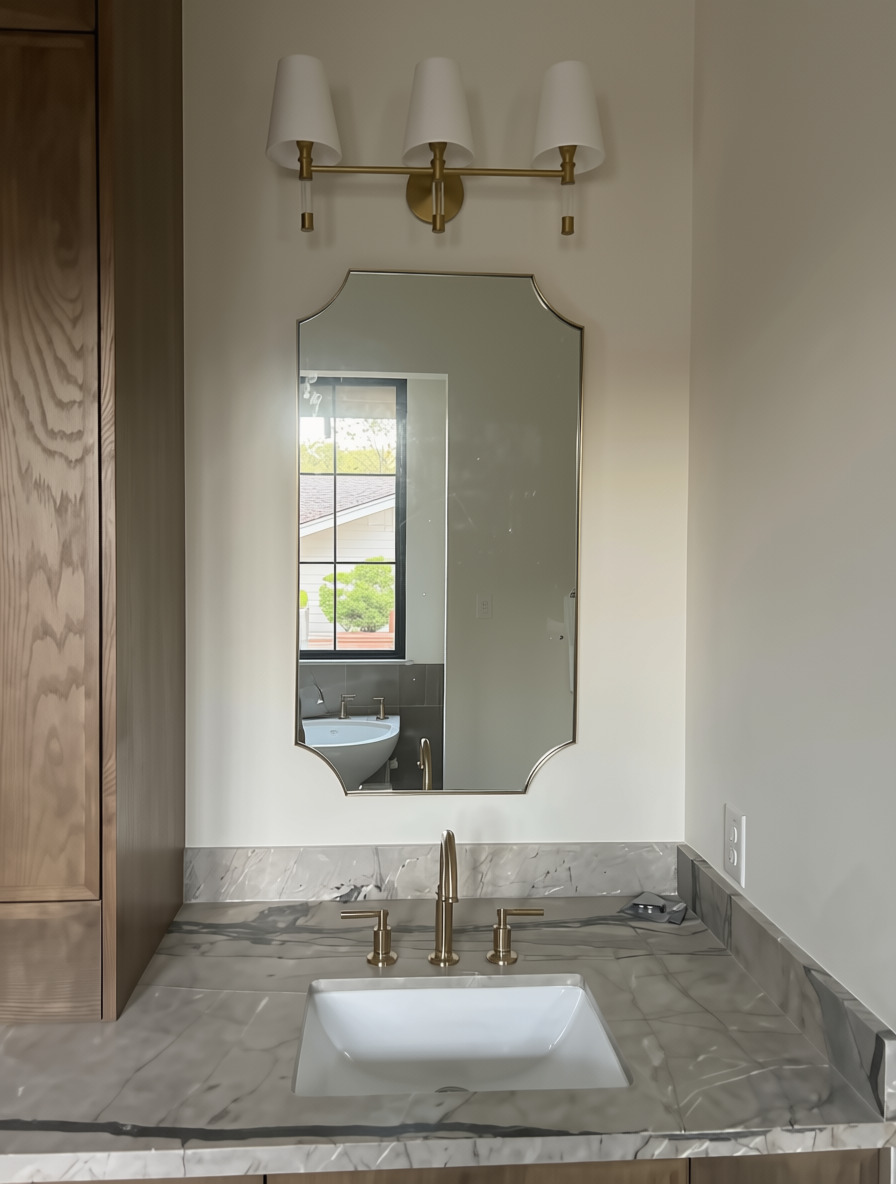 Custom vanity mirror with beveled radius corners beneath brass sconces in Austin, TX