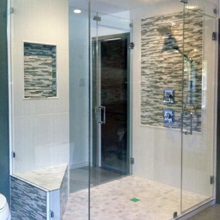 Large frameless 90-degree glass shower enclosure with a mosaic tile accent band