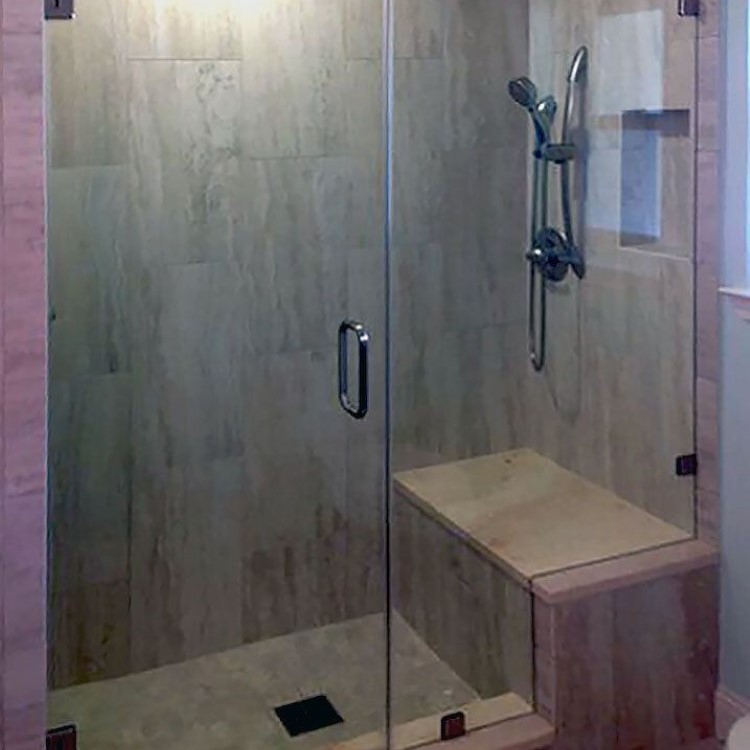 Frameless inline glass shower enclosure with a tiled bench seat