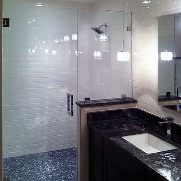 Frameless inline glass shower enclosure set on a tiled half wall