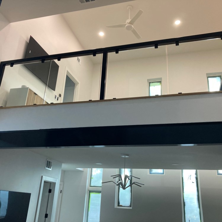 Interior glass railing with a metal top rail on a second-floor landing