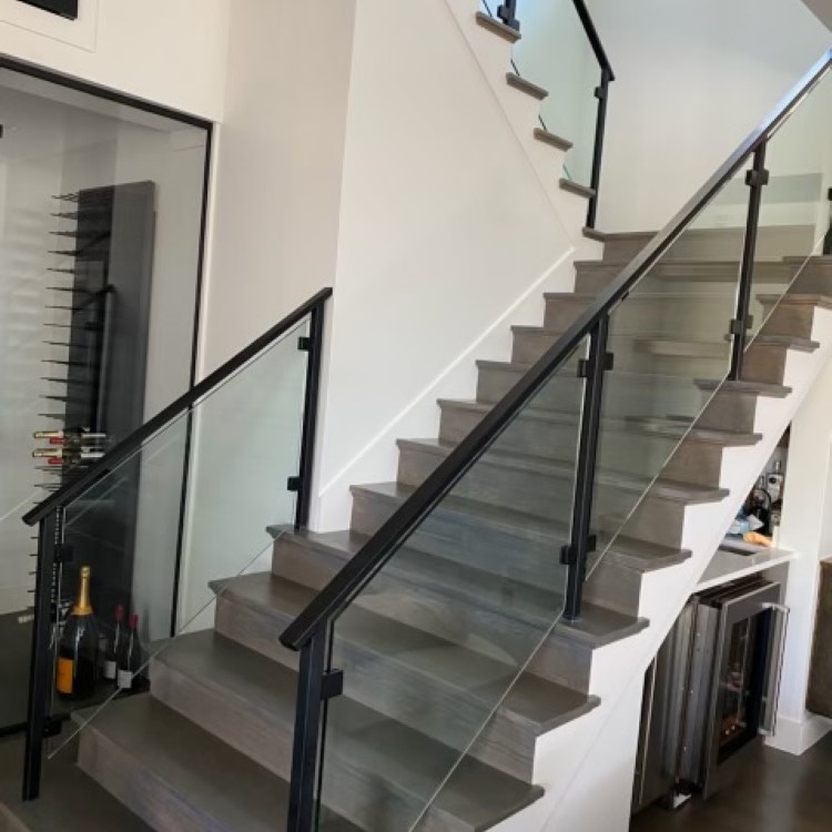Curved glass stair railing beside a sweeping staircase