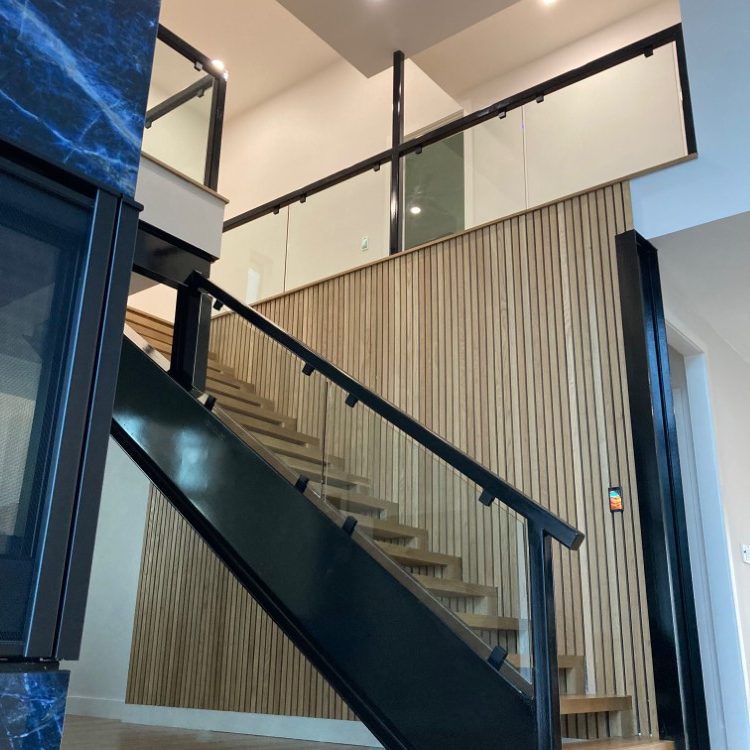 Glass stair railing panels with a black metal top rail