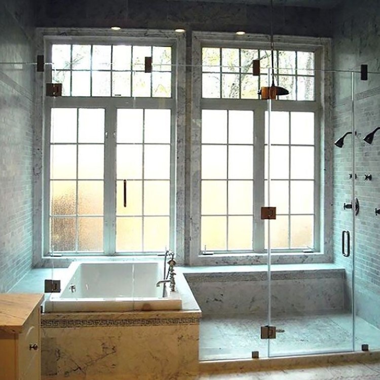 Large frameless inline glass shower enclosure beside a soaking tub
