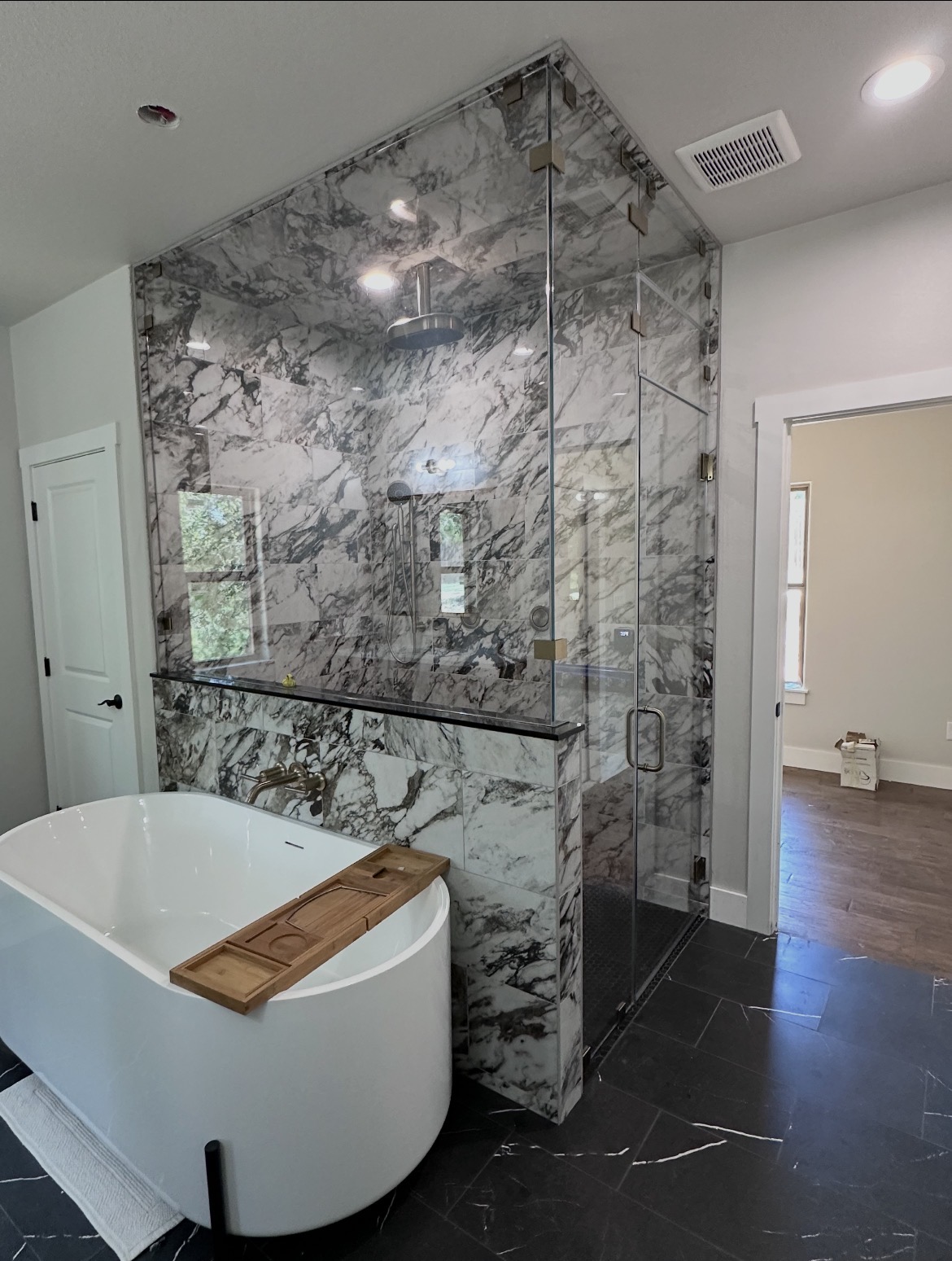 Frameless 90-degree steam shower enclosure with brushed bronze hardware and operable transom in Bastrop, TX