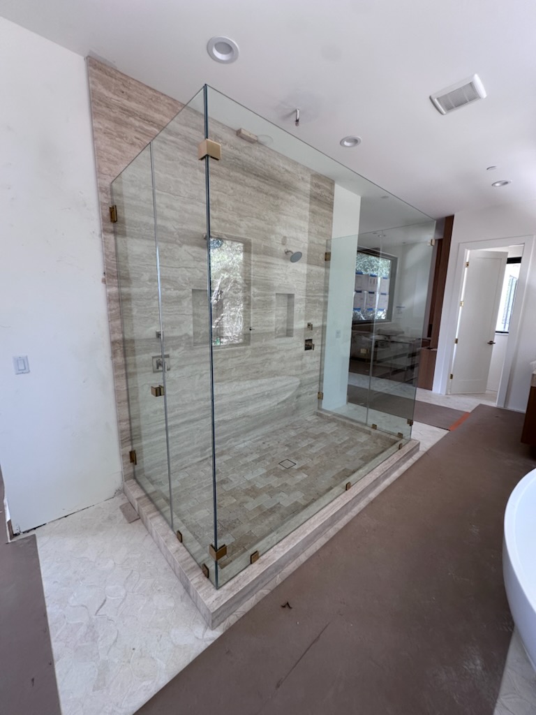 Five-piece double 90-degree custom shower glass enclosure with French gold hardware in a new-build Austin, TX bathroom