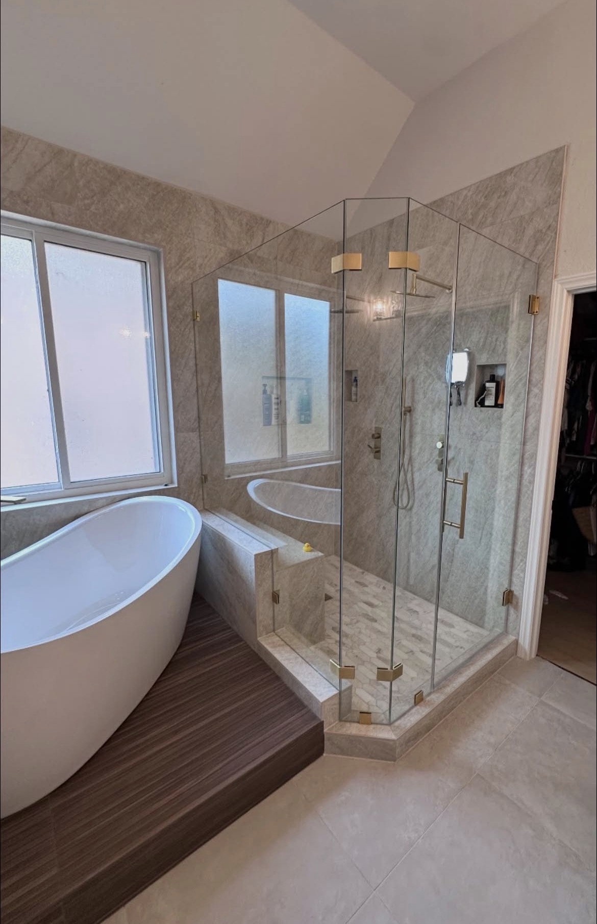 Frameless neo-angle shower enclosure with a ladder pull fitted into a corner beside a raised tub platform in Leander, TX