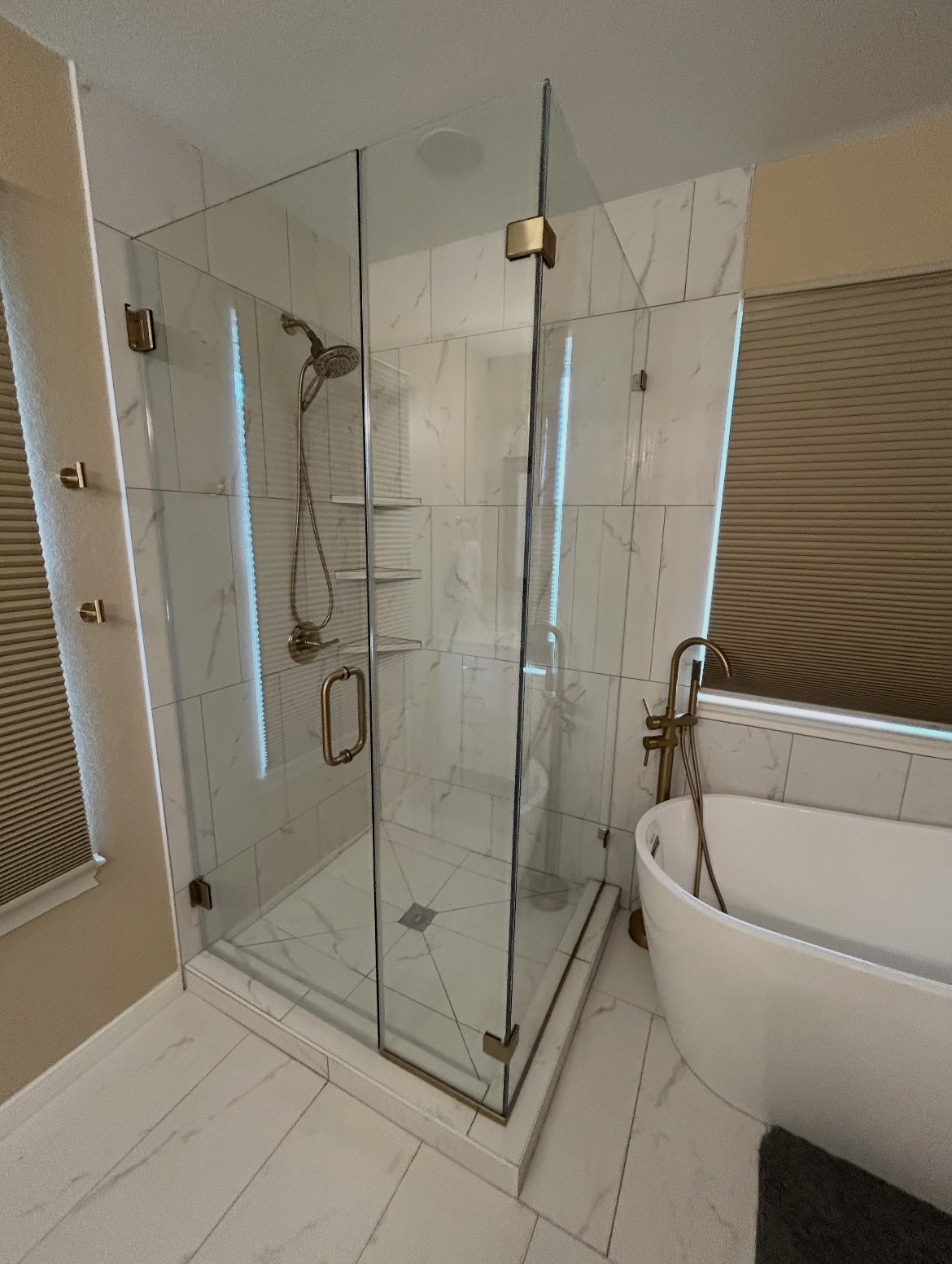 Close view of the Kyle, TX 90-degree frameless enclosure door with a brushed gold handle and hinges