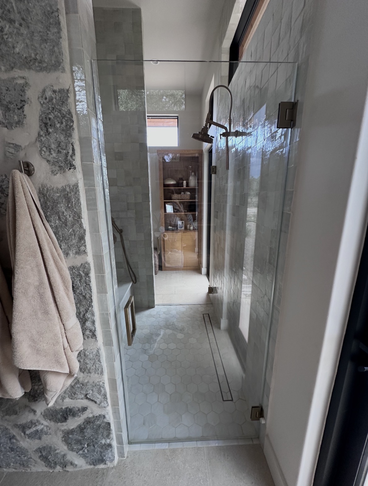One of the two frameless glass doors with brushed bronze hinges on the Wimberley, TX walk-in shower
