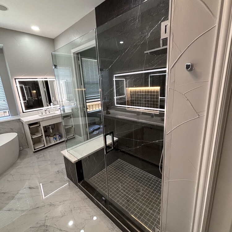Frameless 90-degree glass enclosure around a black marble shower with a bench