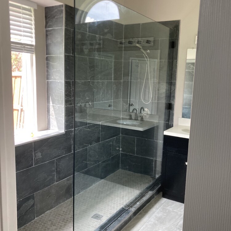 Frameless glass shower enclosure with dark gray tile walls